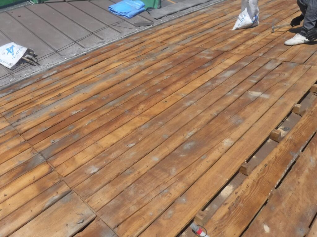 ①足場を設置後、古い瓦を撤去していきます。<br />
屋根板が見える状態になれば解体の完了です。